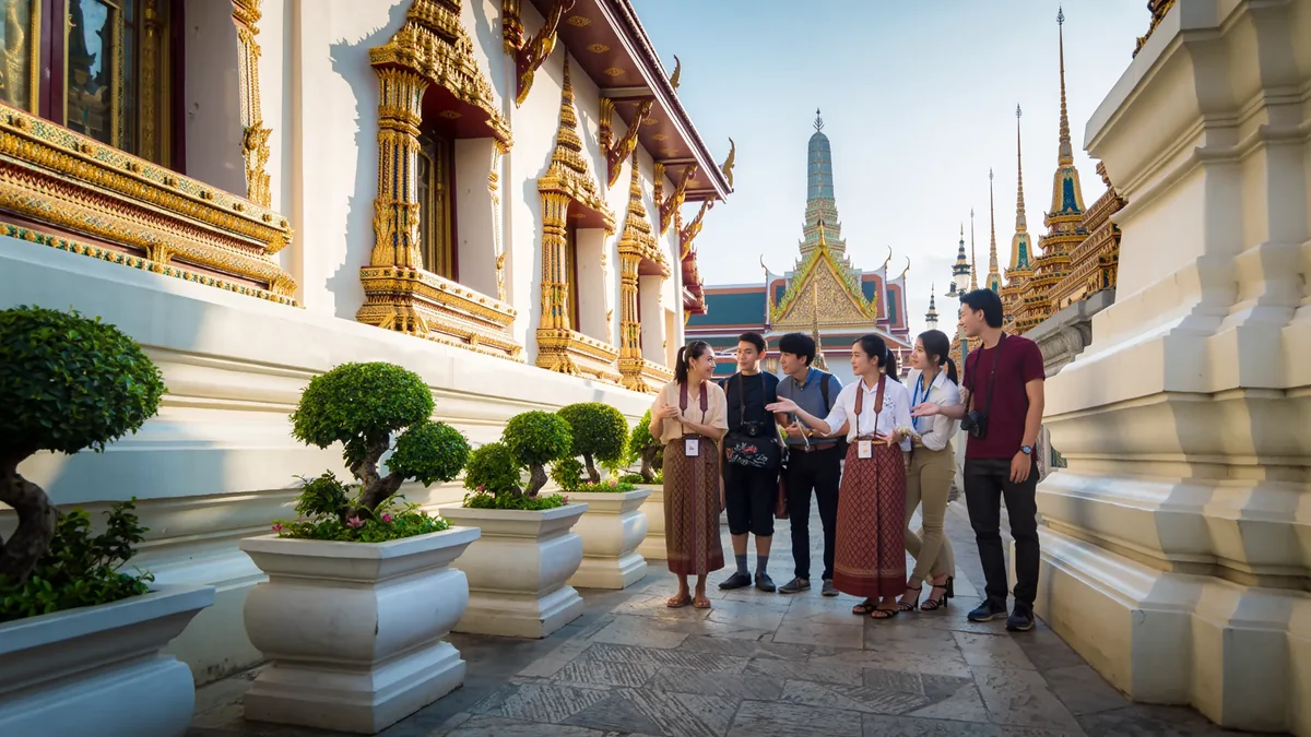 Professional tour guide engaging tourists at ornate Thai Buddhist temple